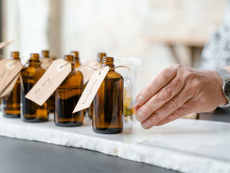 several bottles of amber-colored essential oil bottles lined up on a table with paper labels tied to them