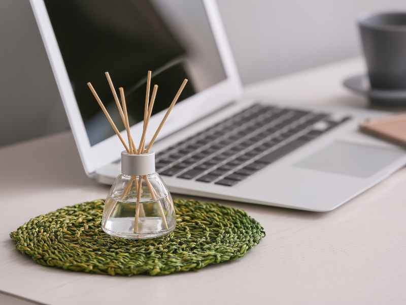 A clear glass aromatherapy diffuser on a desk next to an open laptop